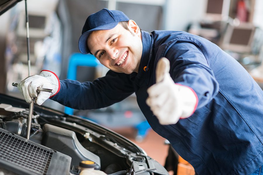 Garage Repair Shop Insurance - Mechanic Giving Thumbs Up to Camera While Working on Vehicle with Hood Open