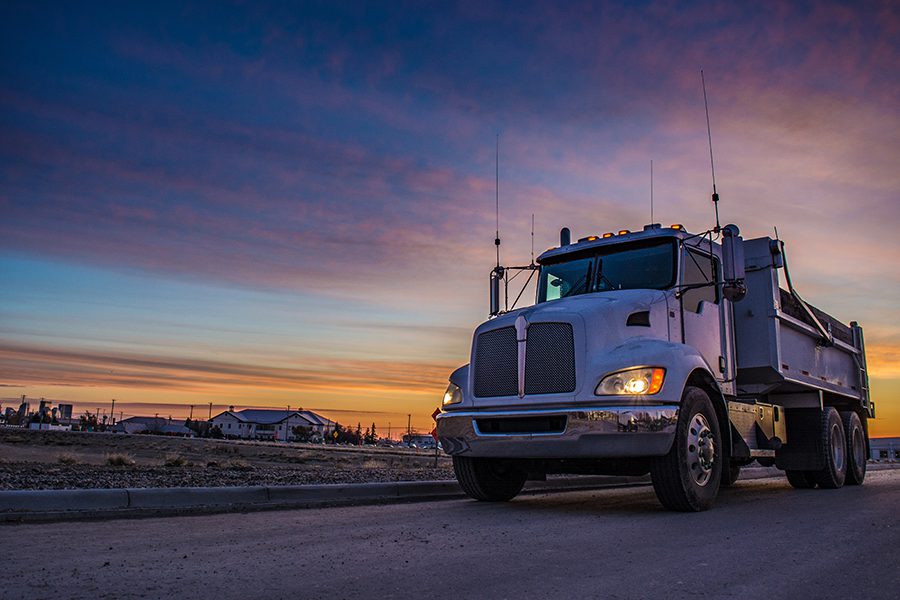 Trucking Insurance - Truck Driving on Road at Dusk